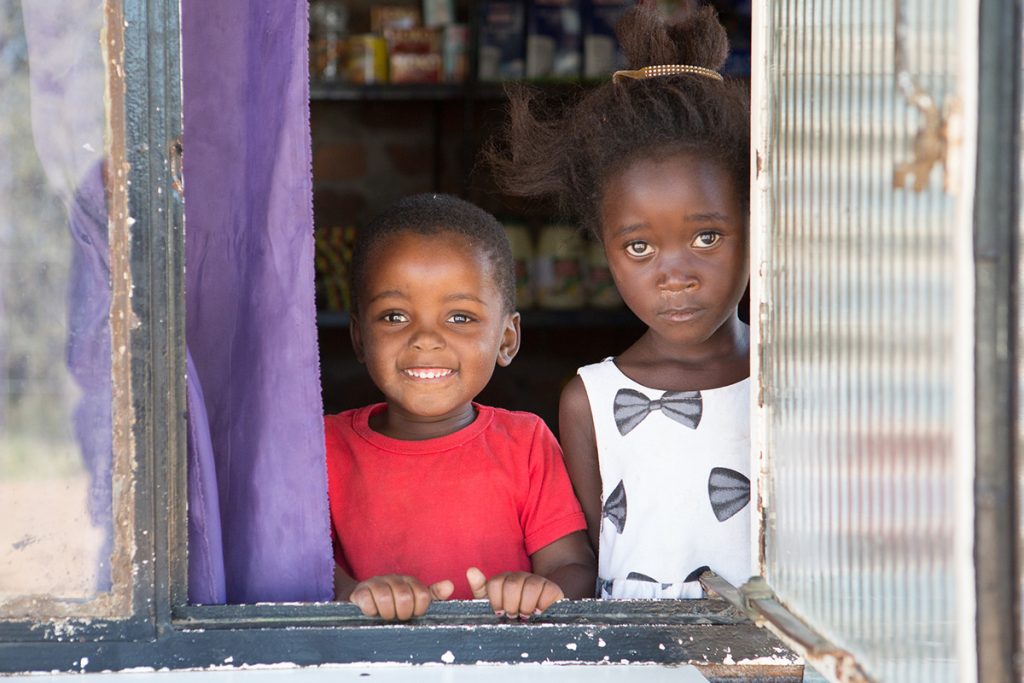 Two children smiling through a window